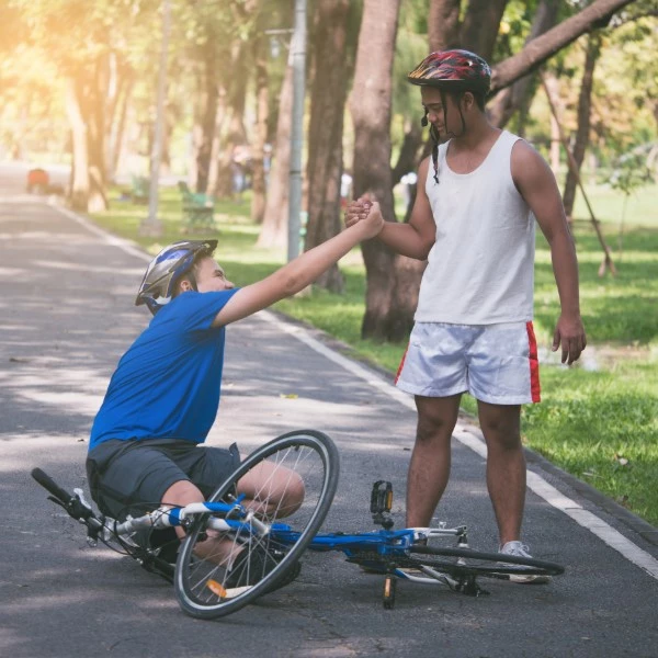 a guy fallen down from bike with a friend picking him up